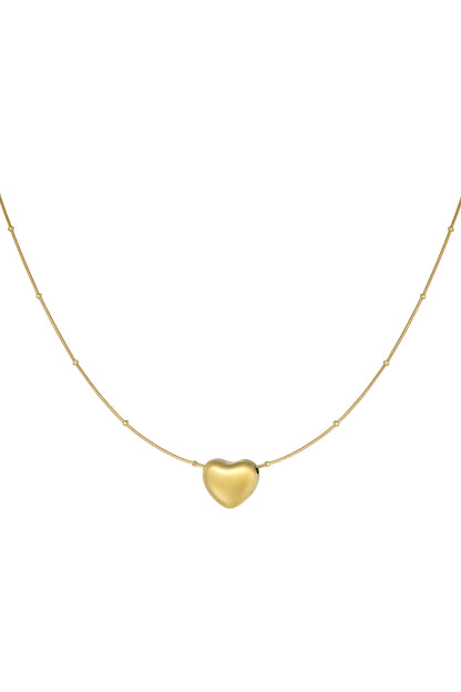 Close-up of a gold heart pendant necklace with a delicate chain featuring spaced beads on a white background