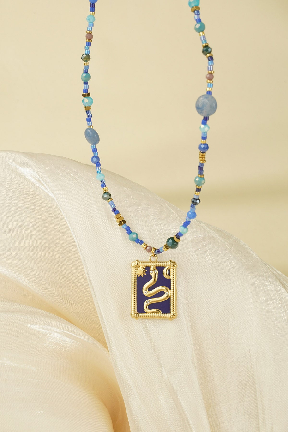 Close-up of the necklace hanging, focusing on the gold snake pendant and intricate beadwork