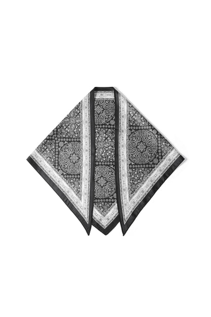 Black and white paisley pattern square silk scarf with patterned border laid flat on white background