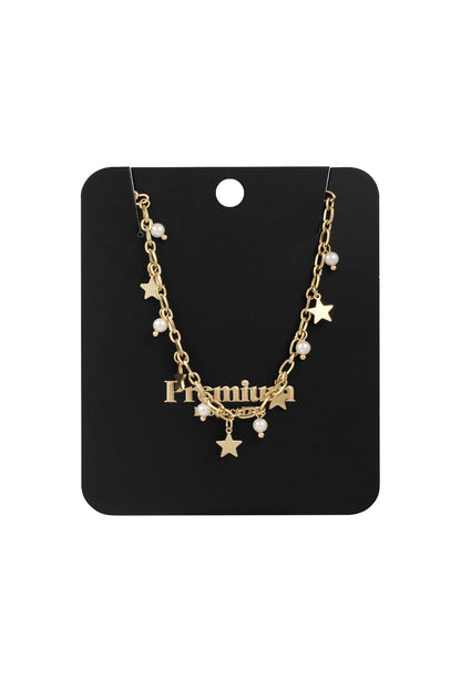 Gold-tone star and pearl charm necklace displayed on a black retail card backing