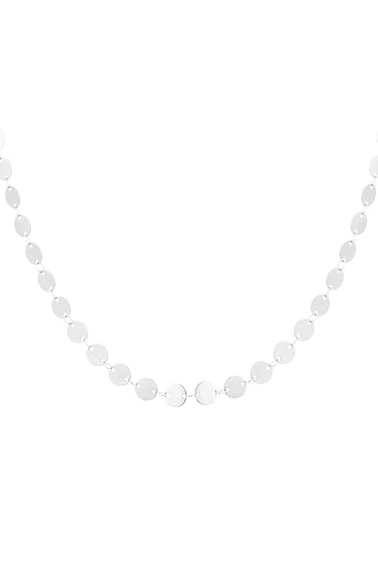 Silver-toned dainty disc chain necklace laid out flat on a white background highlighting its minimal, soft design.