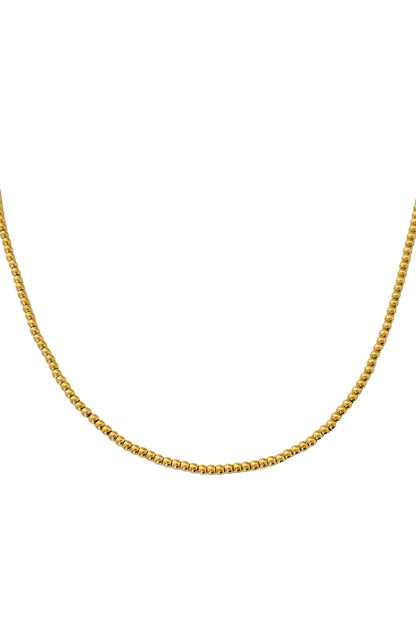 Close-up of gold-toned beaded necklace with small round beads laid out against white background