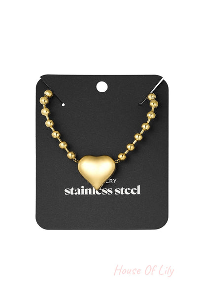 Golden stainless steel beaded heart necklace displayed on black jewelry holder card
