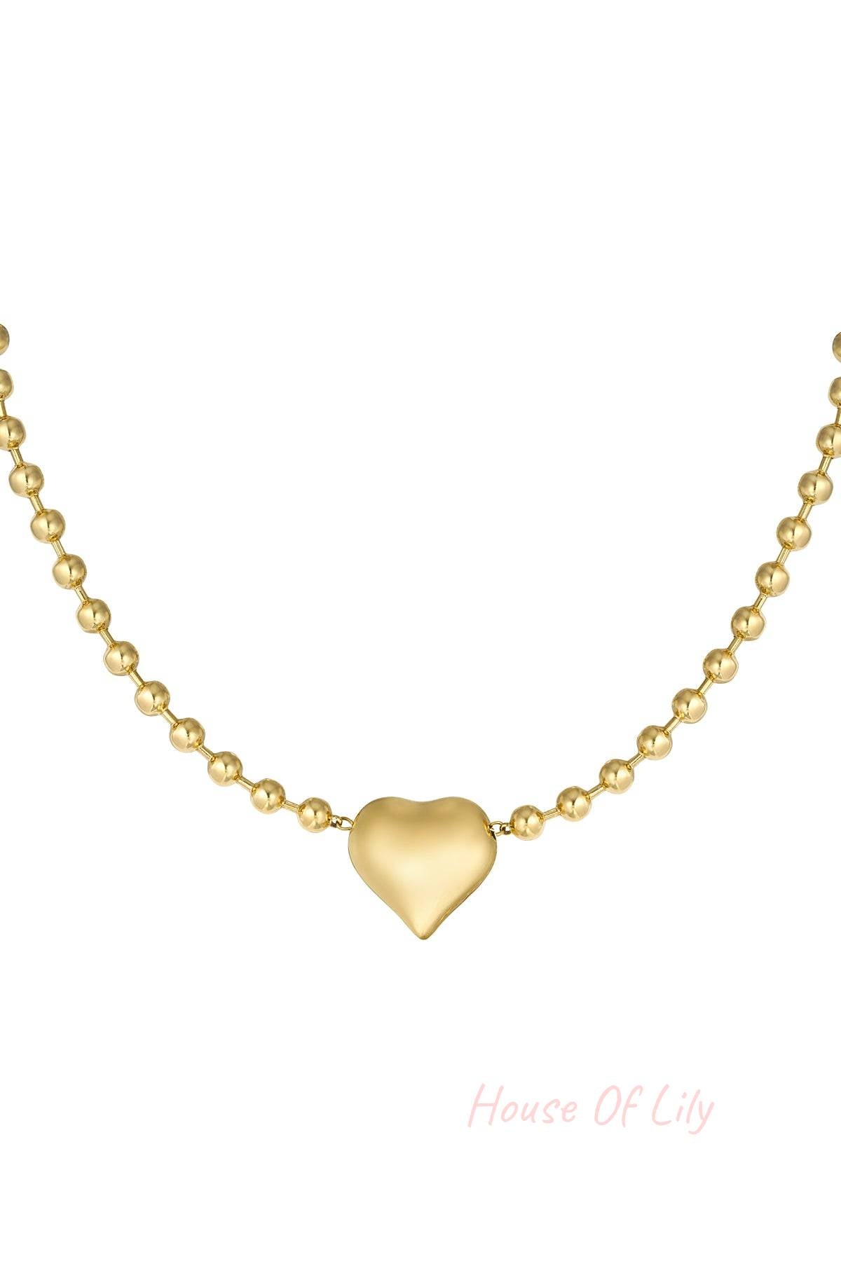 Close-up of golden stainless steel beaded necklace with polished heart pendant