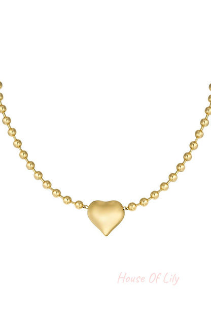 Close-up of golden stainless steel beaded necklace with polished heart pendant