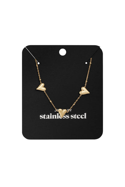 Triple heart gold-tone necklace displayed on a black jewelry card with 'stainless steel' printed, highlighting the product's packaging and material
