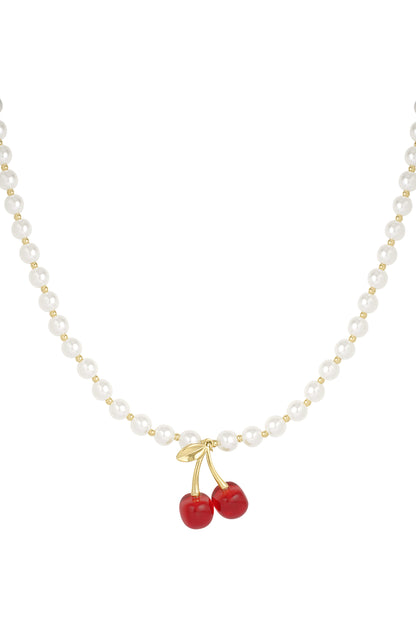 Close-up of pearl necklace with gold-tone beads and red cherry pendant on white background