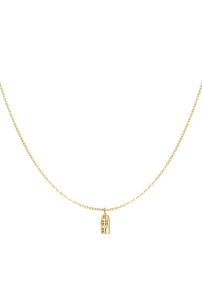Close-up of delicate gold necklace featuring a small cityscape pendant on a fine chain