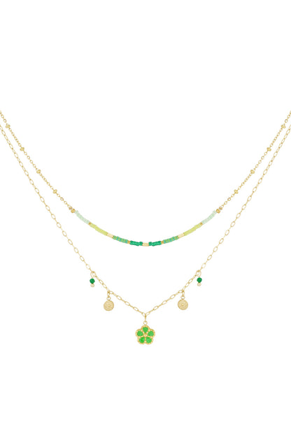 Double-layered gold-tone necklace with green and light green beads and a flower pendant on a white background