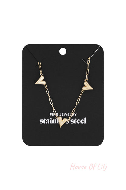 Gold-tone heart link necklace displayed on black jewelry packaging labeled 'stainless steel fine jewelry'