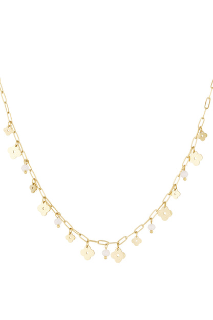 Gold-tone delicate charm necklace featuring clover charms and white bead accents on a white background