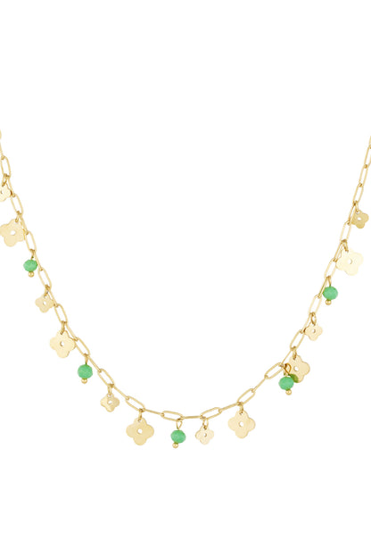 Close-up of gold-tone delicate chain necklace with small clover charms and green bead accents on a white background