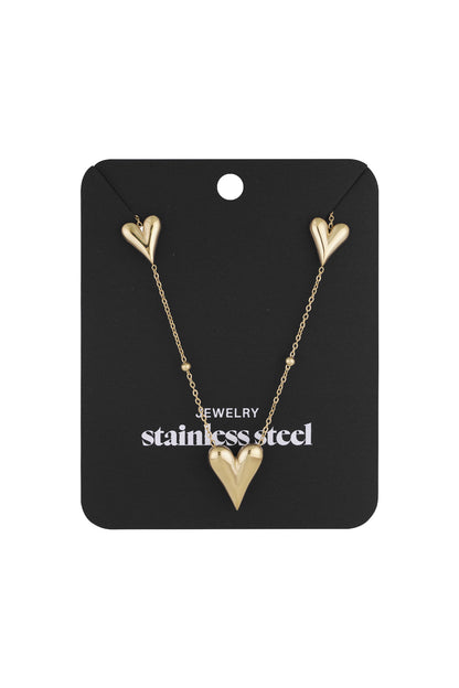 Gold heart charm necklace displayed on black packaging card, labeled stainless steel jewelry