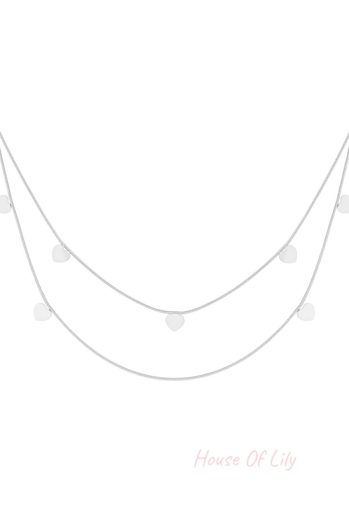 Silver layered necklace with double chains and small heart charms on white background