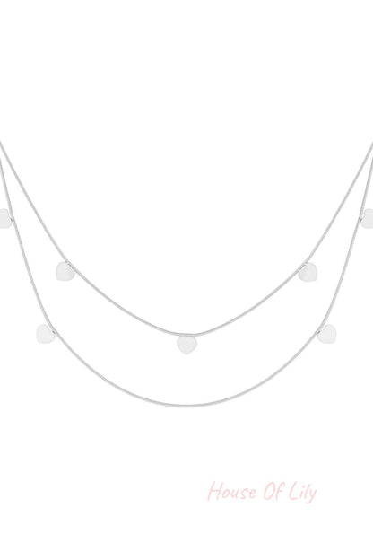 Silver layered necklace with double chains and small heart charms on white background