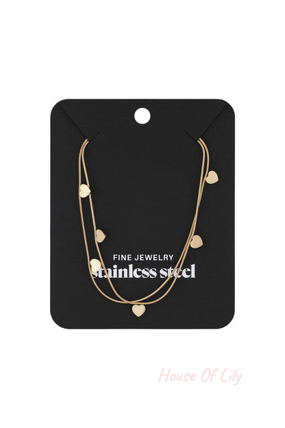 Gold layered heart charm necklace displayed on black jewelry card labeled fine jewelry stainless steel