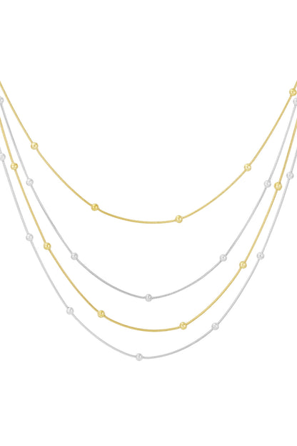 Mixed gold and silver four-strand layered beaded necklace on white background