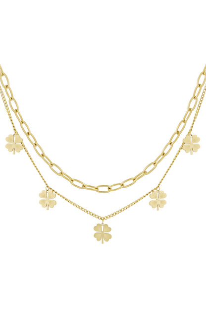 Gold toned double chain layered necklace with clover charms against white background