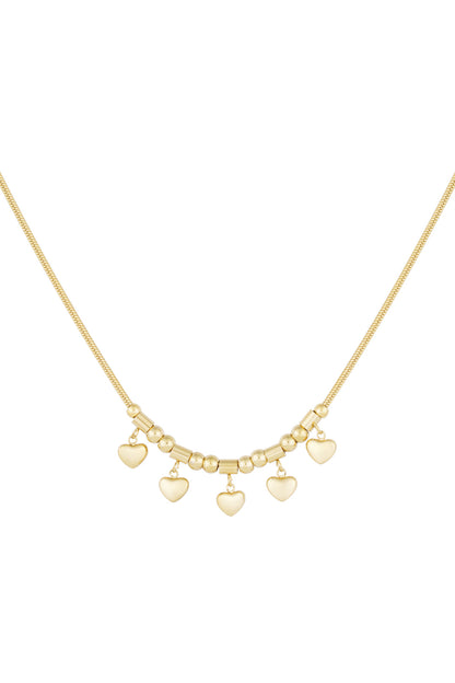Close-up of gold-toned necklace with five small heart charms hanging on a delicate chain with bead details