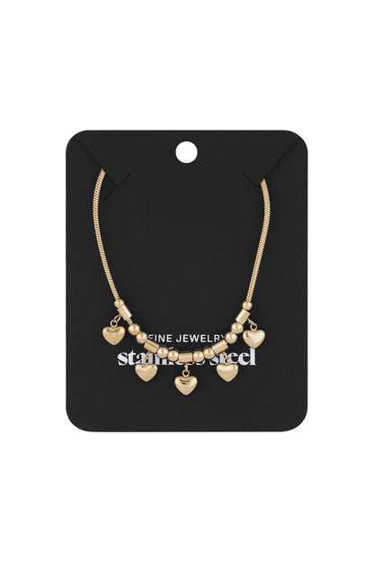 Gold heart charm necklace displayed on a black jewellery card highlighting the elegant charm and design