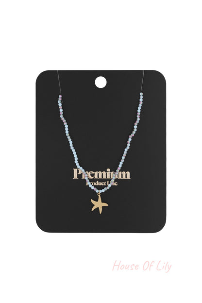 Beaded starfish charm necklace displayed on black premium product card packaging
