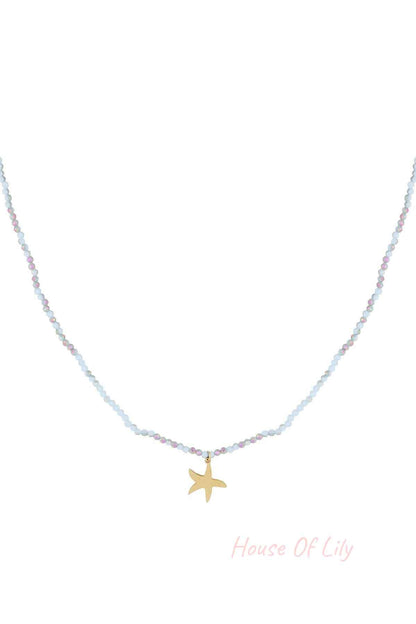 Close-up of a delicate beaded necklace with light blue and iridescent beads and a gold starfish charm pendant on white background