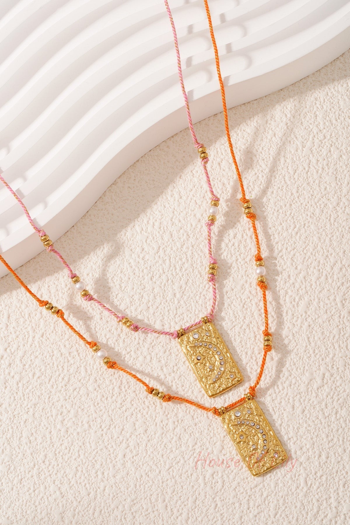 Close-up of pink braided moon pendant necklace with crystal moon design on light background