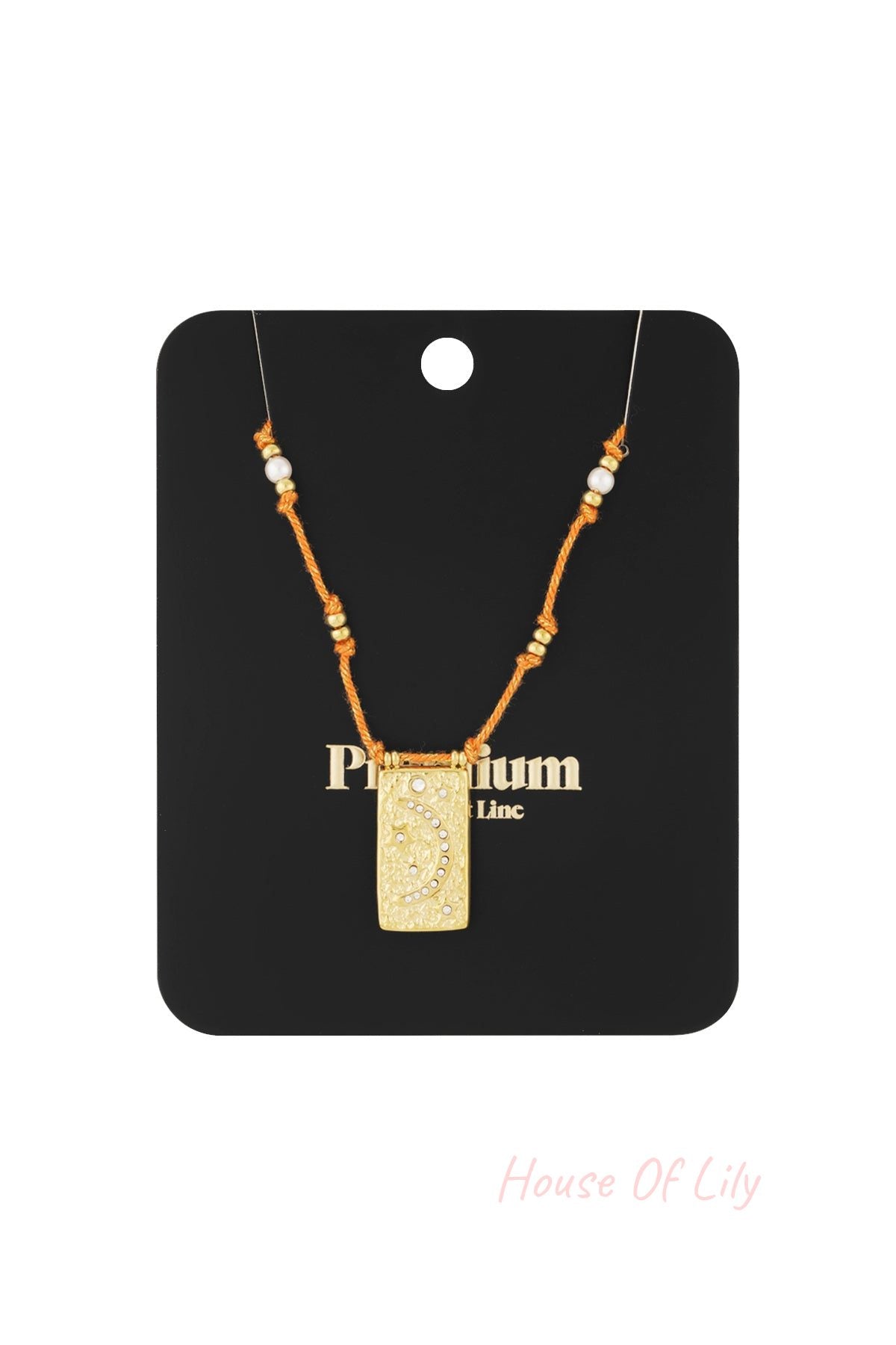 Orange braided moon pendant necklace displayed on black branded card