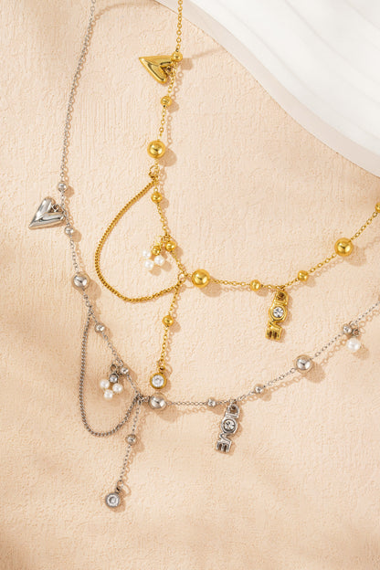 Close-up of gold and silver charm pendant necklaces laid flat on textured peach background showing intricate beaded and charm details