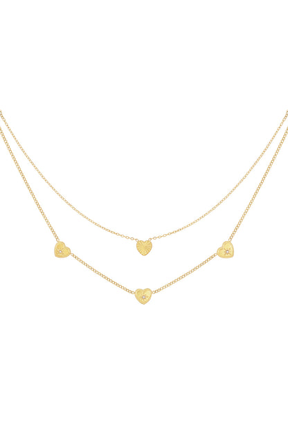 Delicate gold-tone double layered necklace with five small heart charms adorned with rhinestones on white background