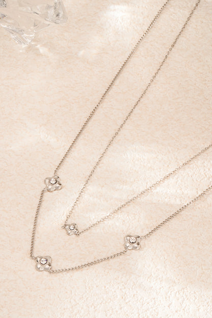 Silver tone layered flower necklace displayed on natural textured stone surface for minimalist aesthetic