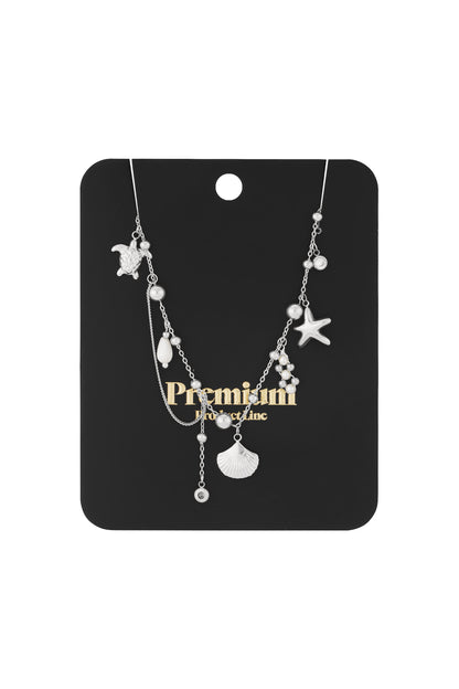 Silver ocean charm necklace with turtle, scallop, starfish and pearl charms on white background
