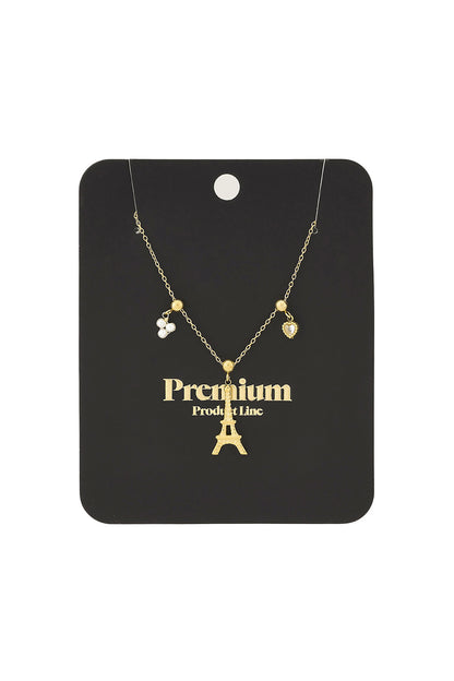 Gold and silver Eiffel Tower charm necklaces with pearl cluster and heart charms displayed on stone surface