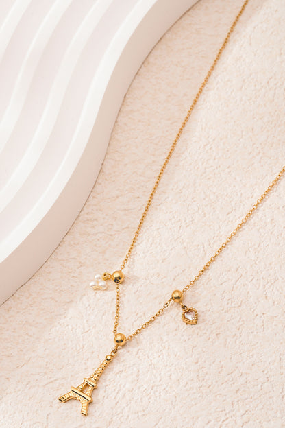 Silver version of Eiffel Tower charm necklace with pearl and heart charms on white background