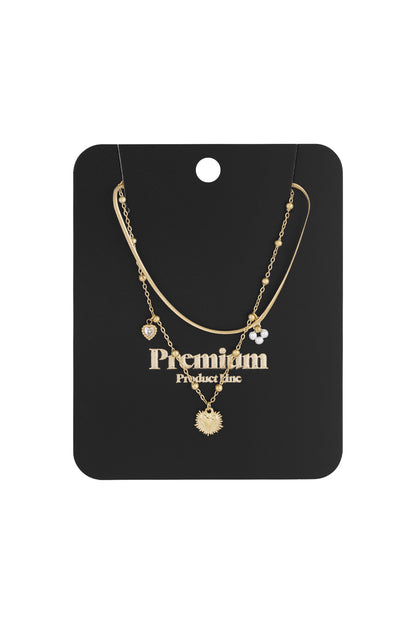 Gold-tone layered heart charm necklace displayed on black card with Premium Product Inc. branding