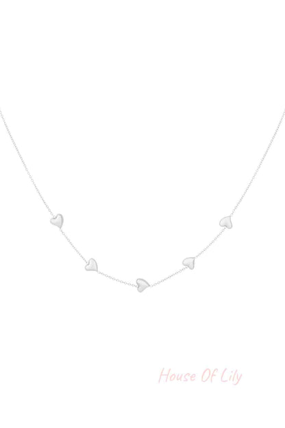 Silver dainty necklace with five small heart-shaped charms evenly spaced on a fine chain, isolated on white background