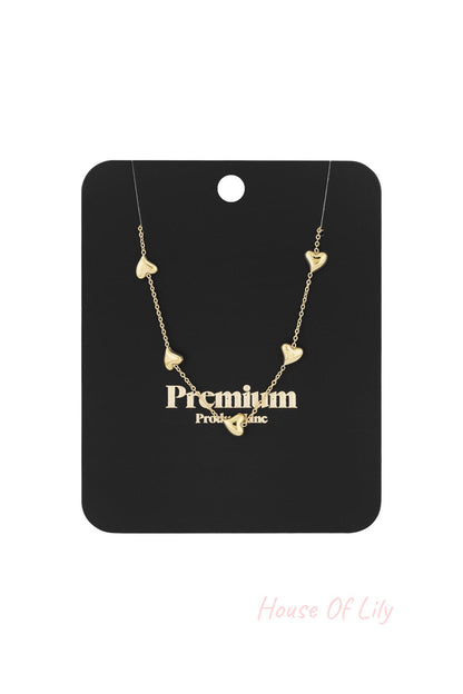 Gold heart charm necklace displayed on a black Premium product line packaging card