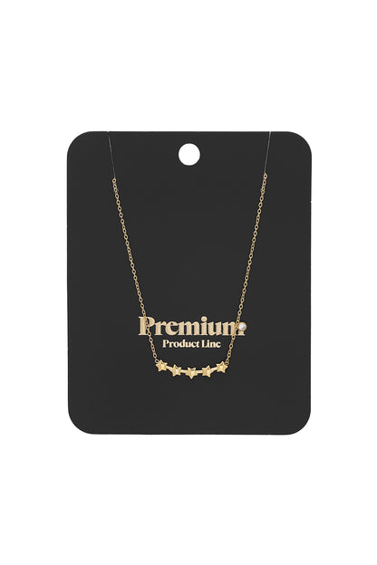 Gold star cluster necklace displayed on black premium product line packaging card