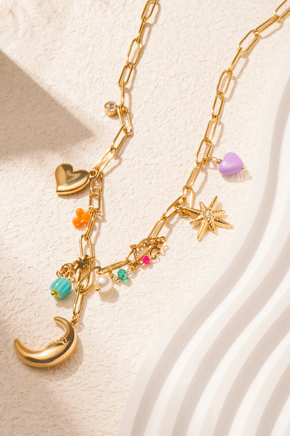 Close-up of charm pendant necklace on textured cream surface highlighting moon charm and colourful beads