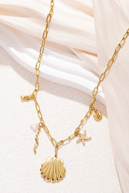 Close-up image of the gold charm necklace arranged elegantly on beige fabric highlighting the shiny shell and starfish charms.
