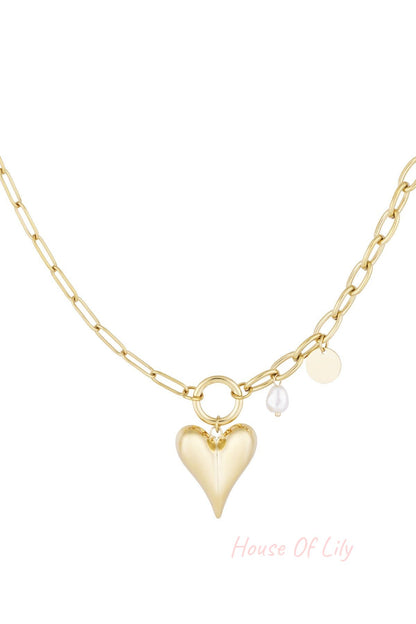 Gold-tone chunky paperclip chain necklace with heart-shaped pendant, pearl and coin charms on white background