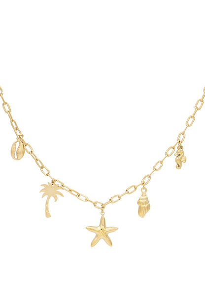 Close-up of gold charm necklace with seaside motifs including starfish, palm tree, shell, seahorse, and cowrie shell on medium-link chain