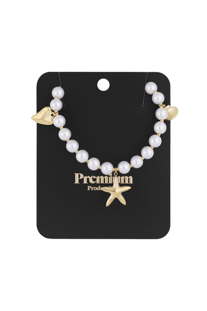 Pearl charm necklace displayed on black premium card with gold starfish, shell, and heart charms
