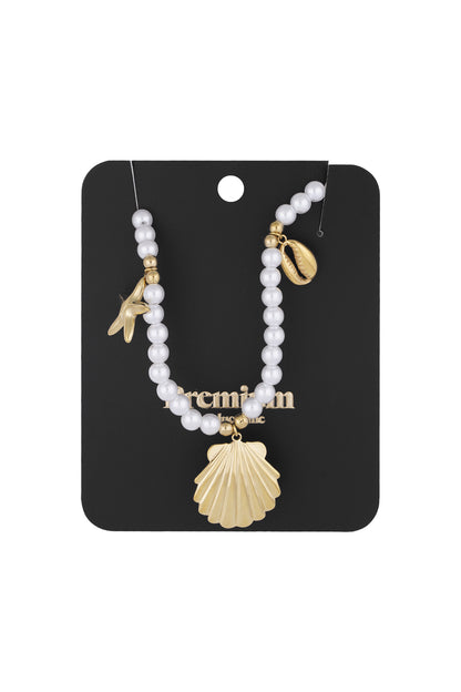 Pearl charm necklace presented on black display card showing detailed sea-inspired gold charms