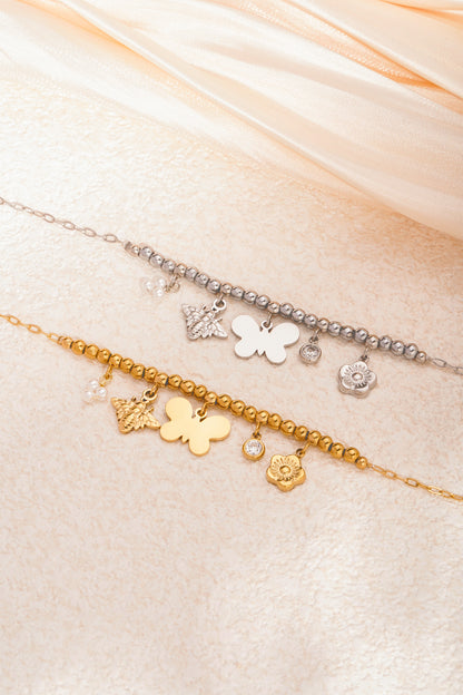 Silver and gold charm beaded necklaces placed on beige fabric surface