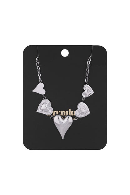 Silver multi heart charm necklace displayed on black premium packaging card