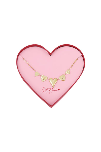 Gold heart charm necklace displayed in a pink heart-shaped box with red edges, featuring five unique heart pendants.