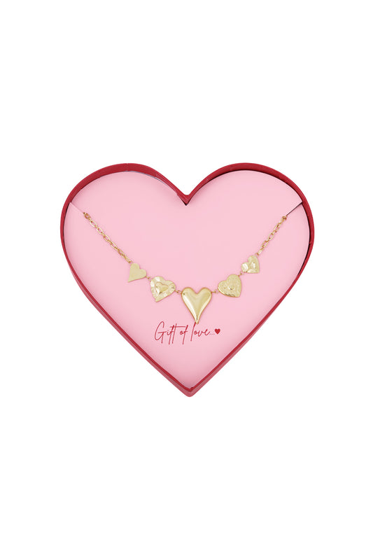 Gold heart charm necklace displayed in a pink heart-shaped box with red edges, featuring five unique heart pendants.