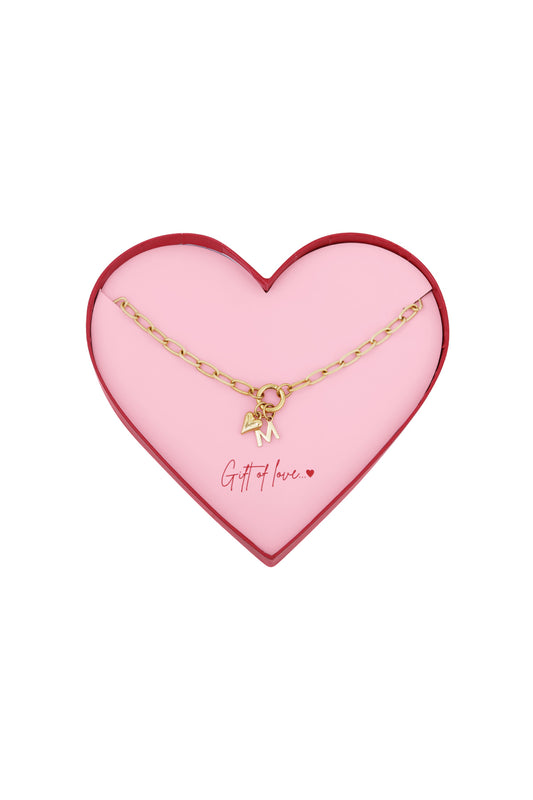 Gold-tone chunky link necklace with heart and letter M pendants presented in a pink heart-shaped box with ‘Gift of love’ inscription
