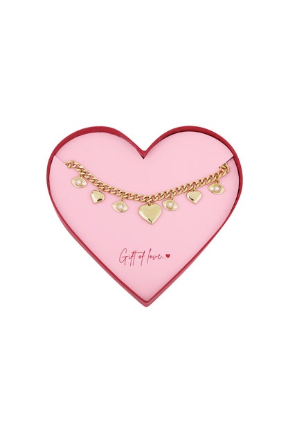 Gold-tone charm bracelet displayed in a pink heart-shaped gift box with red edges and 'Gift of love...' text.